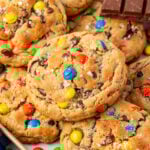 Monster cookies stacked on a sheet pan.