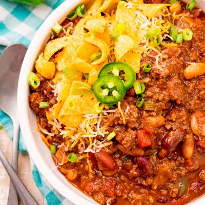 Overhead photo of a bowl of slow cooker chili on a teal gingham napkin.