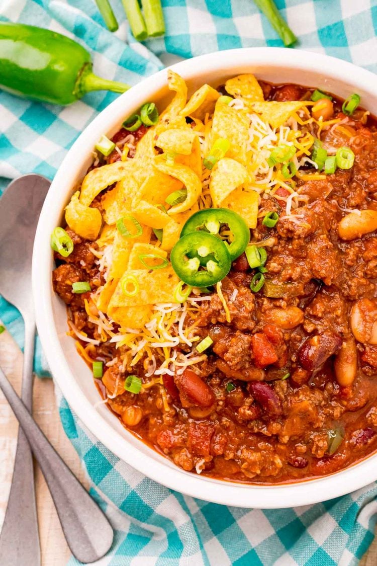 Overhead photo of a bowl of slow cooker chili on a teal gingham napkin.