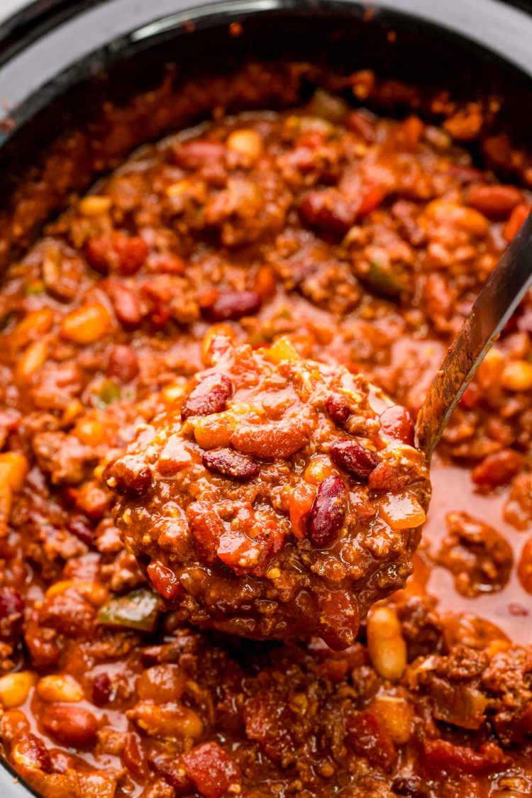 Close up photo of a ladle scooping chili out of a crockpot.