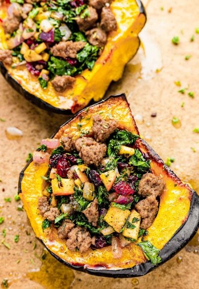 Close up photo of baked stuffed acorn squash on a parchment lined baking sheet.