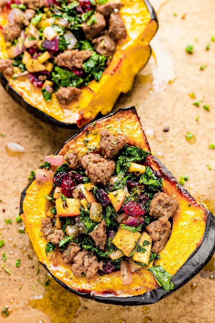 Close up photo of baked stuffed acorn squash on a parchment lined baking sheet.