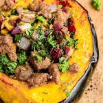 Close up photo of stuffed acorn squash on parchment paper.