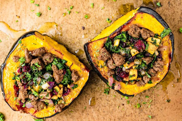 Stuffed acorn squash halves on a baking sheet lined with parchment paper.