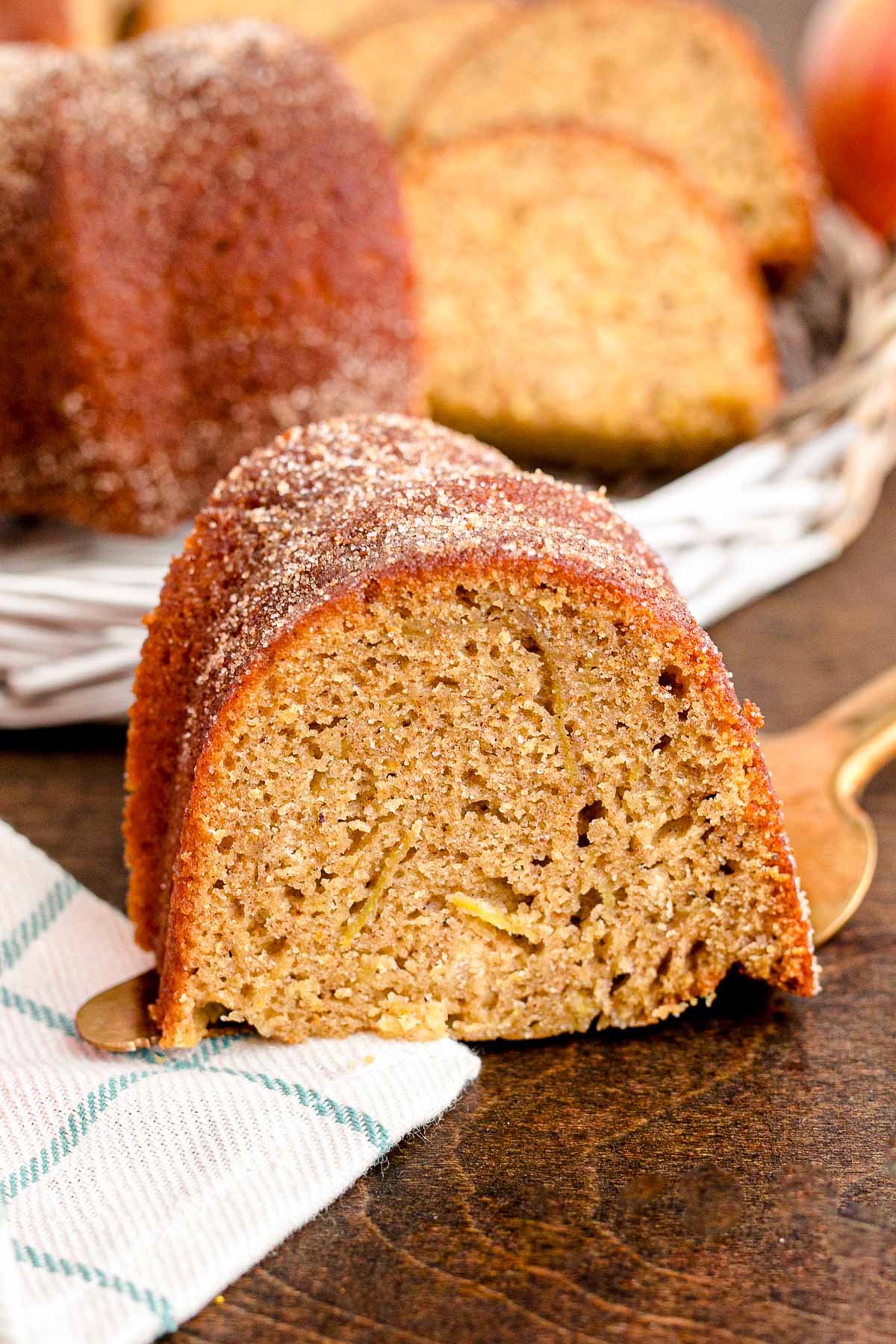 Close up photo of a slice of apple cider donut cake on a cake server on a wooden table. 