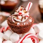 Close up photo of hot chocolate brownie bite on a mound of mini marshmallows and candy canes.