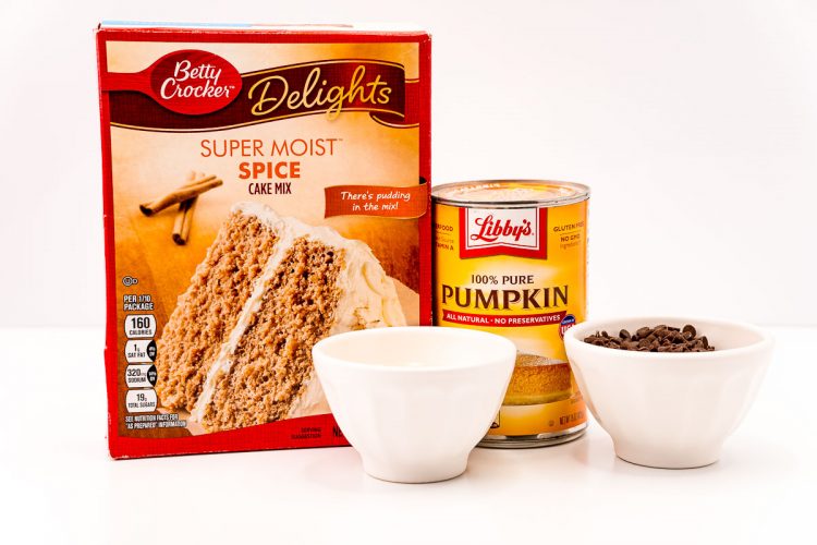 Ingredients to make pumpkin chocolate chip cookies from a cake mix on a white table.