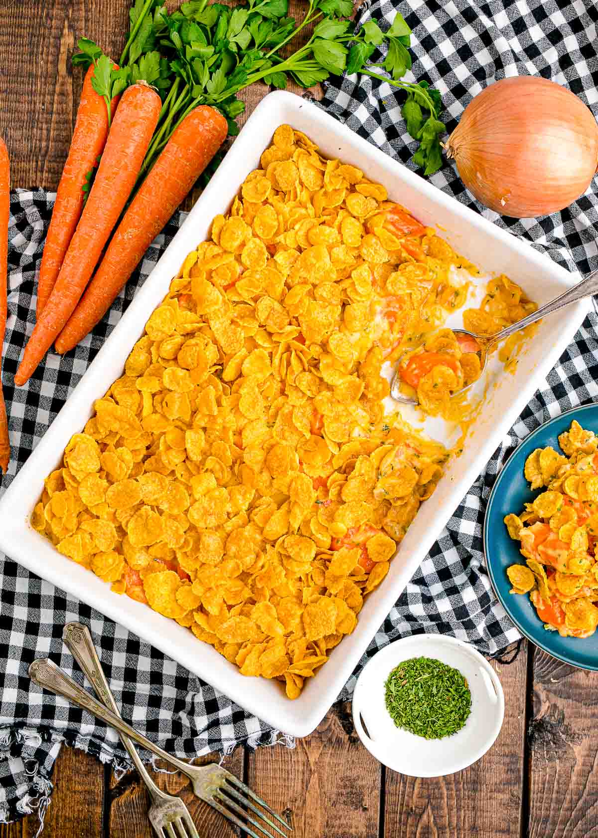 Overhead photo of a white casserole dish filled with carrot casserole on a black and white checkered napkin.