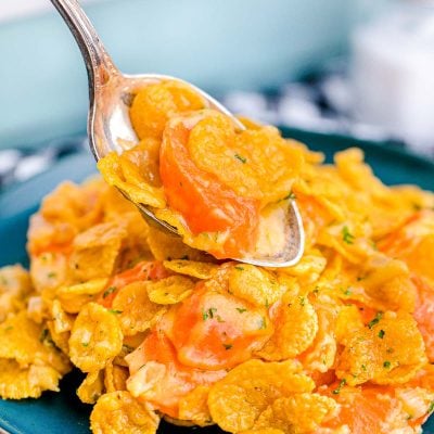 Close up photo of carrot casserole being scooped onto a blue plate.