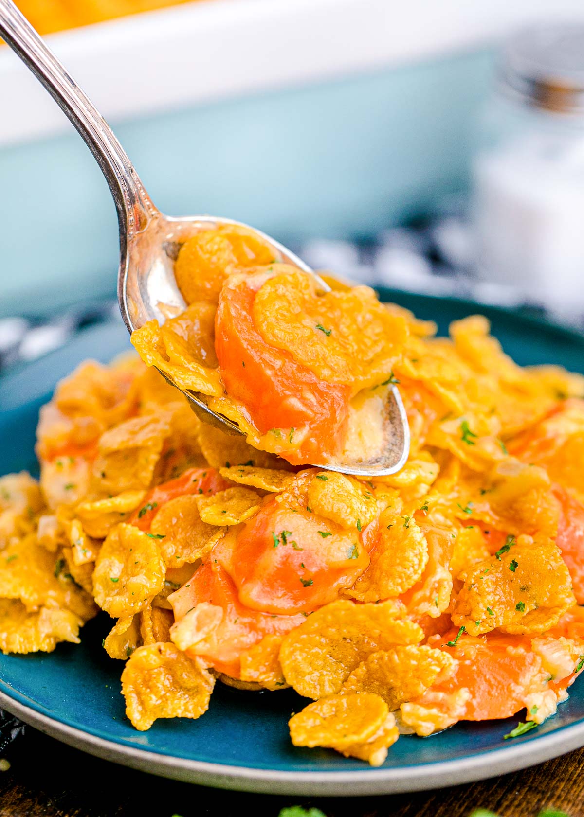 Close up photo of carrot casserole being scooped onto a blue plate.