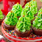 Close up photo of christmas tree brownie bites on a small plate filled with rainbow sprinkles.