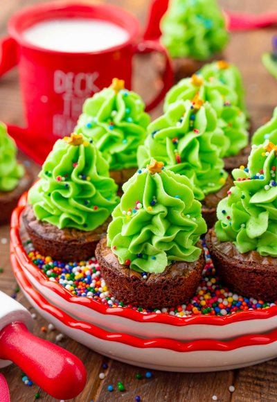 Close up photo of christmas tree brownie bites on a small plate filled with rainbow sprinkles.