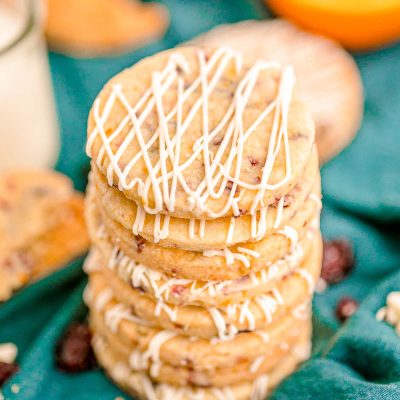 Close up photo of a stack of cranberry orange shortbread cookies on a teal napkin.