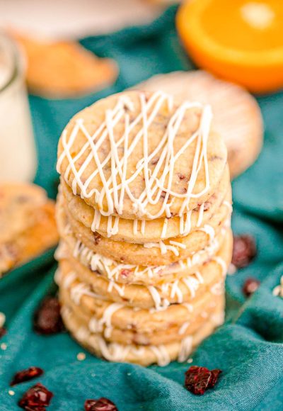 Close up photo of a stack of cranberry orange shortbread cookies on a teal napkin.