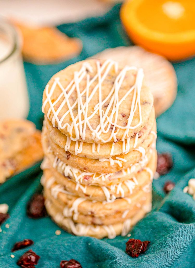 Close up photo of a stack of cranberry orange shortbread cookies on a teal napkin.