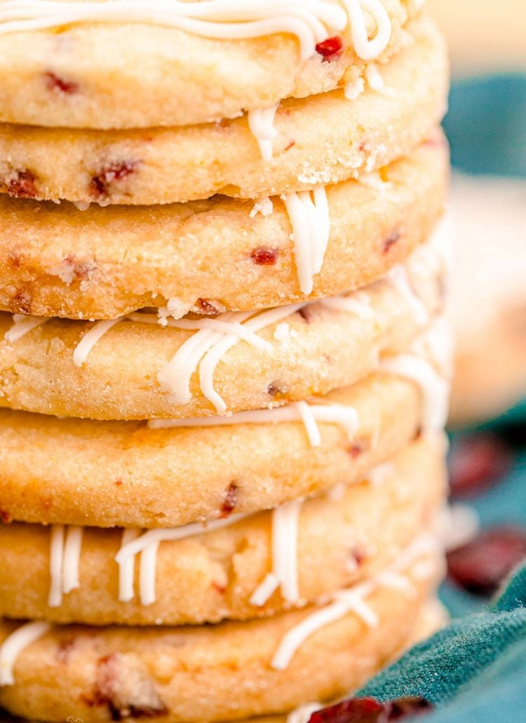 Close up photo of a stack of cranberry orange shortbread cookies on a teal napkin.