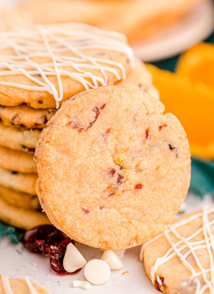 Close up photo of a stack of cranberry orange cookies with one cookie leaning against the stack.