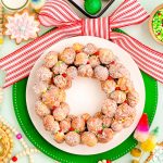 Overhead photo of a donut hole platter designed to look like a christmas wreath with holiday decorations scattered around it.