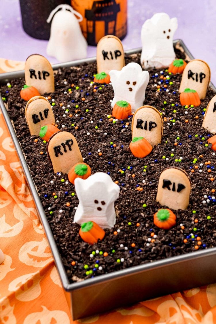 Halloween graveyard dirt cake in a 9x13-inch pan on an orange napkin.