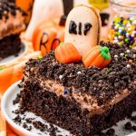 Close up photo of a slice of chocolate Halloween Cake on a white plate on an orange napkin.