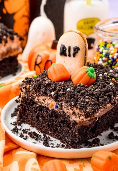 Close up photo of a slice of chocolate Halloween Cake on a white plate on an orange napkin.