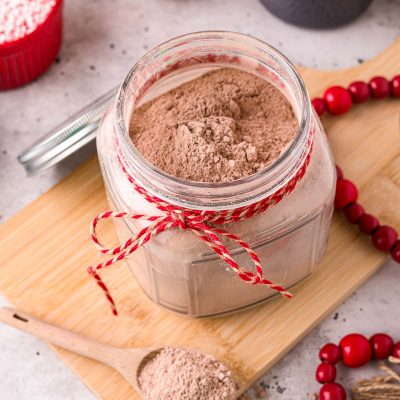 Close up photo of a jar with homemade hot chocolate mix in it with a baking twine ribbon around the neck of the jar.