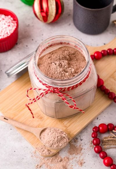 Close up photo of a jar with homemade hot chocolate mix in it with a baking twine ribbon around the neck of the jar.