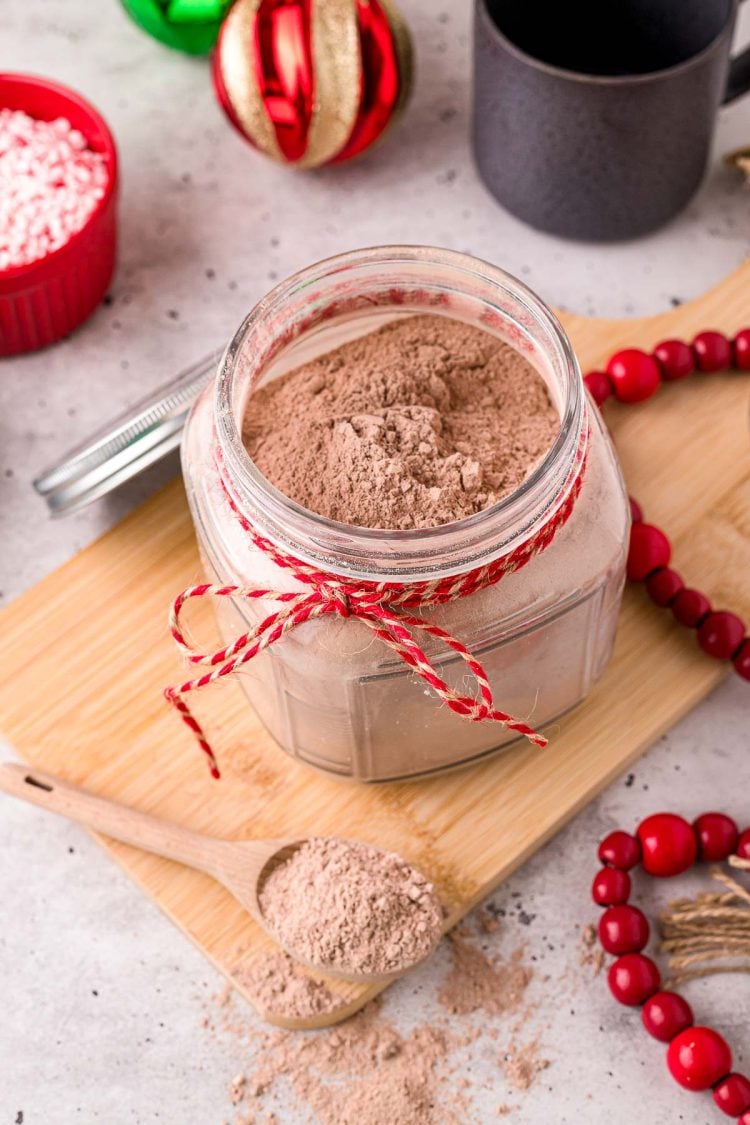 Close up photo of a jar with homemade hot chocolate mix in it with a baking twine ribbon around the neck of the jar.