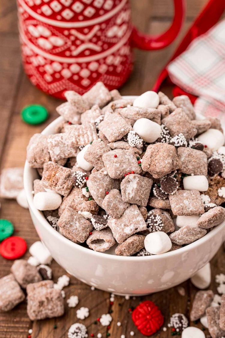 Close up photo of a white bowl filled with hot chocolate muddy buddies.