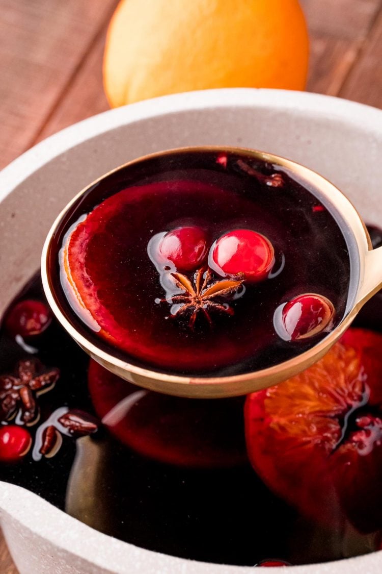 A ladle scooping mulled wine out of a small saucepot.