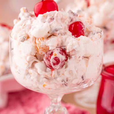 Close up photo of a glass serving dish with fruit ambrosia salad in it.