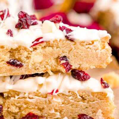 Close up photo of two Starbucks copycat cranberry bliss bars stacked on parchment paper.