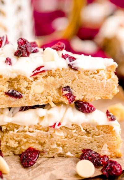 Close up photo of two Starbucks copycat cranberry bliss bars stacked on parchment paper.