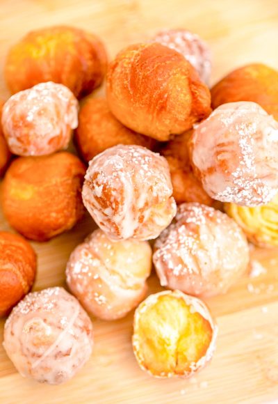 Close up photo of fried donut holes on a wooden cutting board.