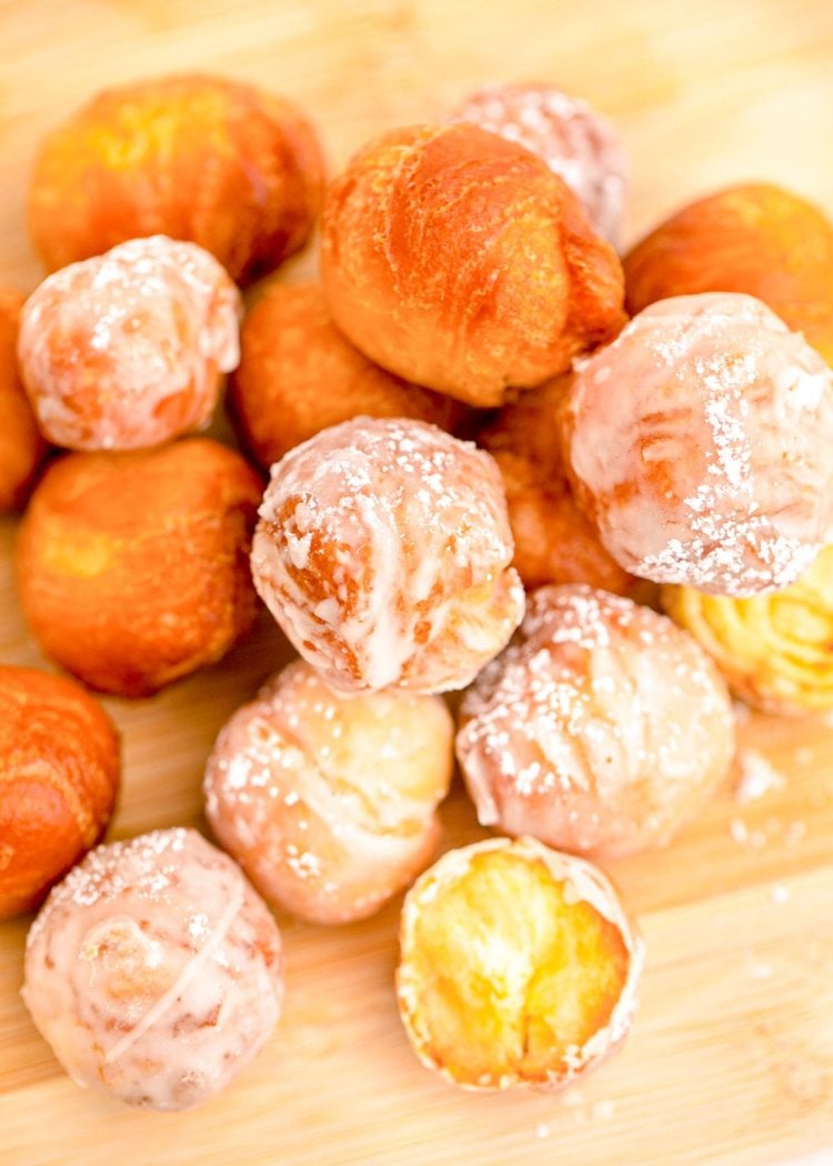Close up photo of fried donut holes on a wooden cutting board.