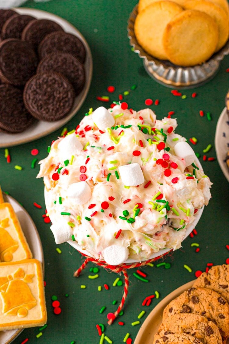 A small bowl of Elf inspired dessert dip on a green surface with cookies around it.