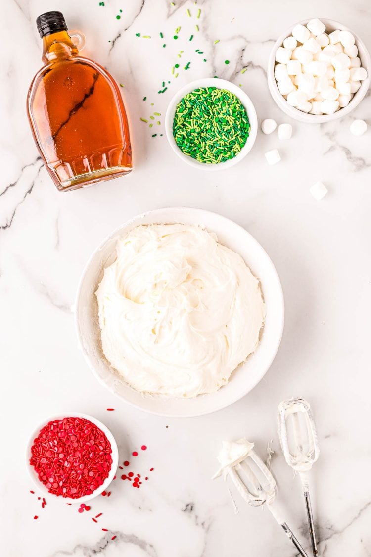 Overhead photo of cream cheese, fluff, and powdered sugar mixed in a white bowl.