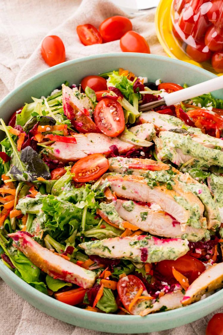 Close up photo of a grilled chicken salad with green goddess dressing.