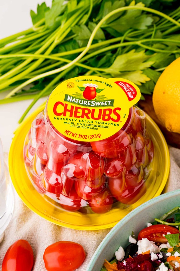 Close up photo of a package of NatureSweet Cherubs on a table with ingredients to make a salad around it.