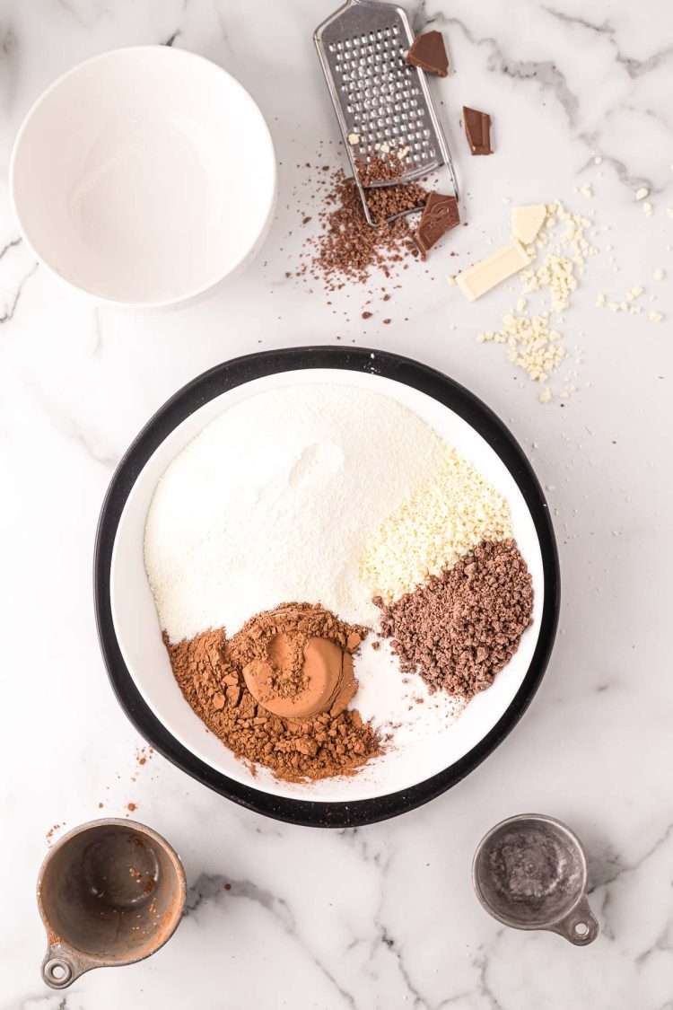 overhead photo of ingredients being added to a mixing bowl to make homemade hot chocolate mix.