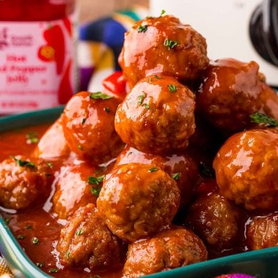 Close up photo of a teal plate filled with hot pepper jelly cocktail meatballs.