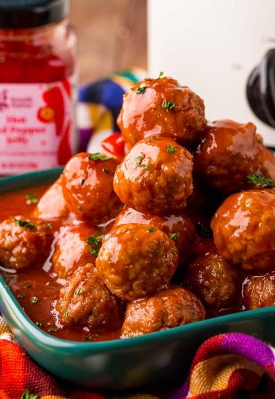 Close up photo of a teal plate filled with hot pepper jelly cocktail meatballs.