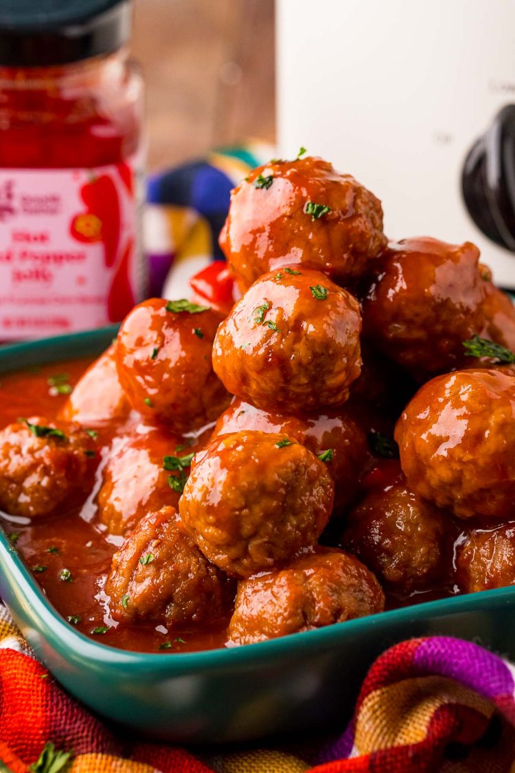 Close up photo of a teal plate filled with hot pepper jelly cocktail meatballs.