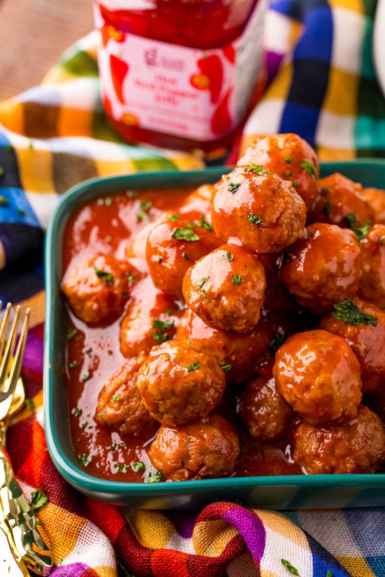 Close up photo of a teal plate filled with hot pepper jelly cocktail meatballs.