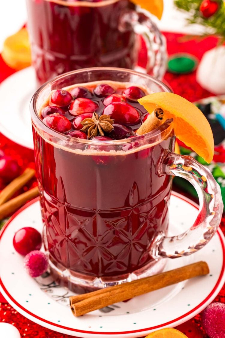 Close up photo of kinder punch in a mug on a white plate surrounded by holiday decorations.