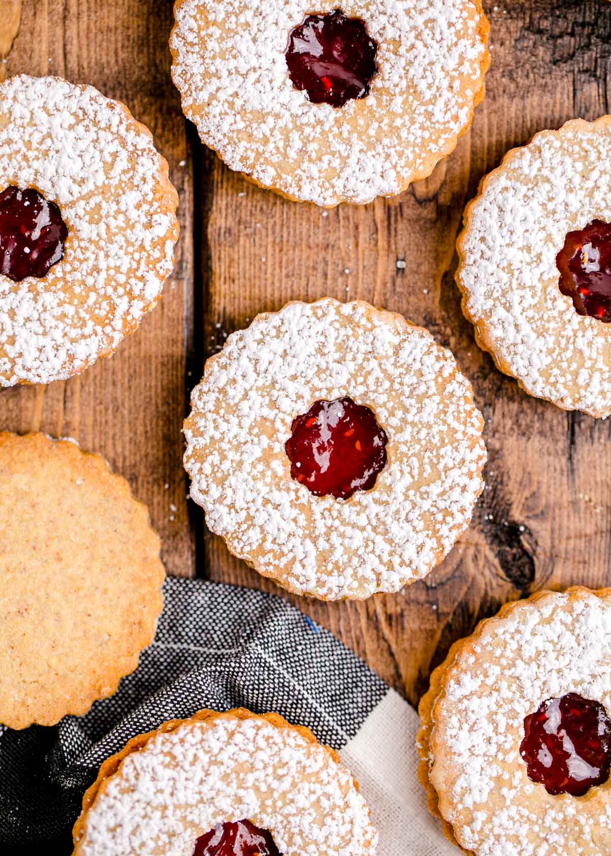 Overhead photo of linzer cookies on a wooden table with a black and white napkin.