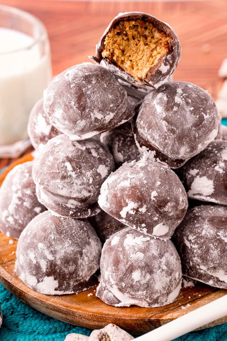 Close up photo of muddy buddy balls (puppy chow truffles) on a wooden plate on a teal trivet.