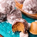 Close up photo of puppy chow truffles on a teal woven placemat with muddy buddies around them.