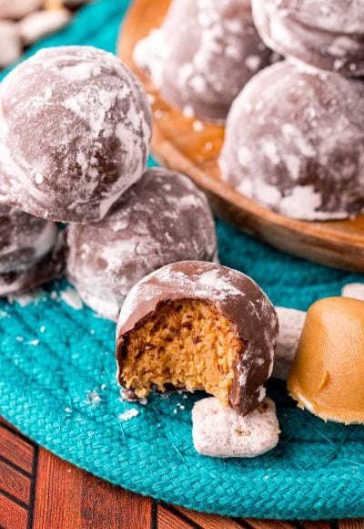 Close up photo of puppy chow truffles on a teal woven placemat with muddy buddies around them.