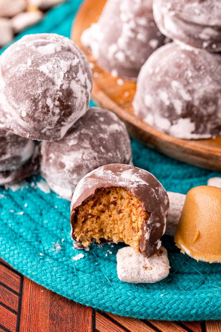 Close up photo of puppy chow truffles on a teal woven placemat with muddy buddies around them.